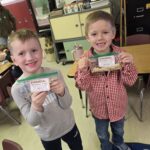 Two students holding small bags of reindeer food!