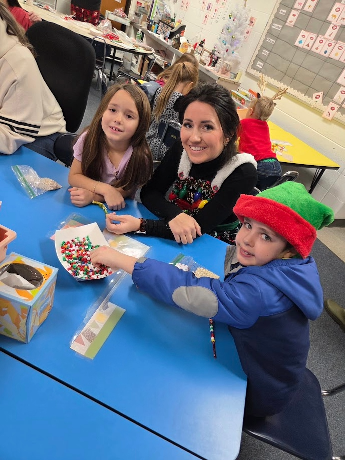 Students and a parent doing a bead craft.